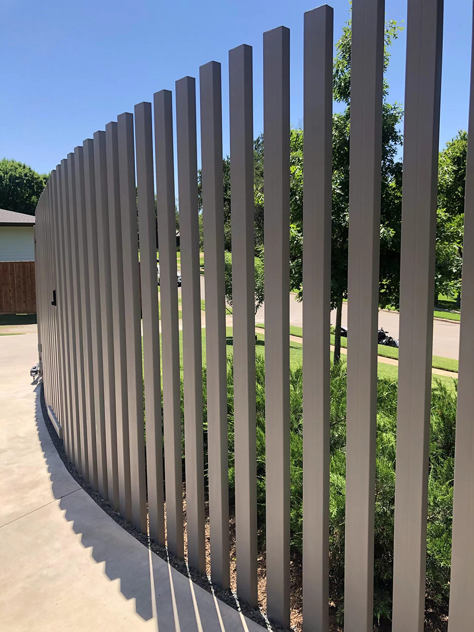Photo of vertical slat alumninum fencing on a curved driveway